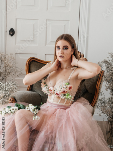 Obraz na płótnie A girl with voluminous hair poses in a pink dress with flowers in her hands w salonie