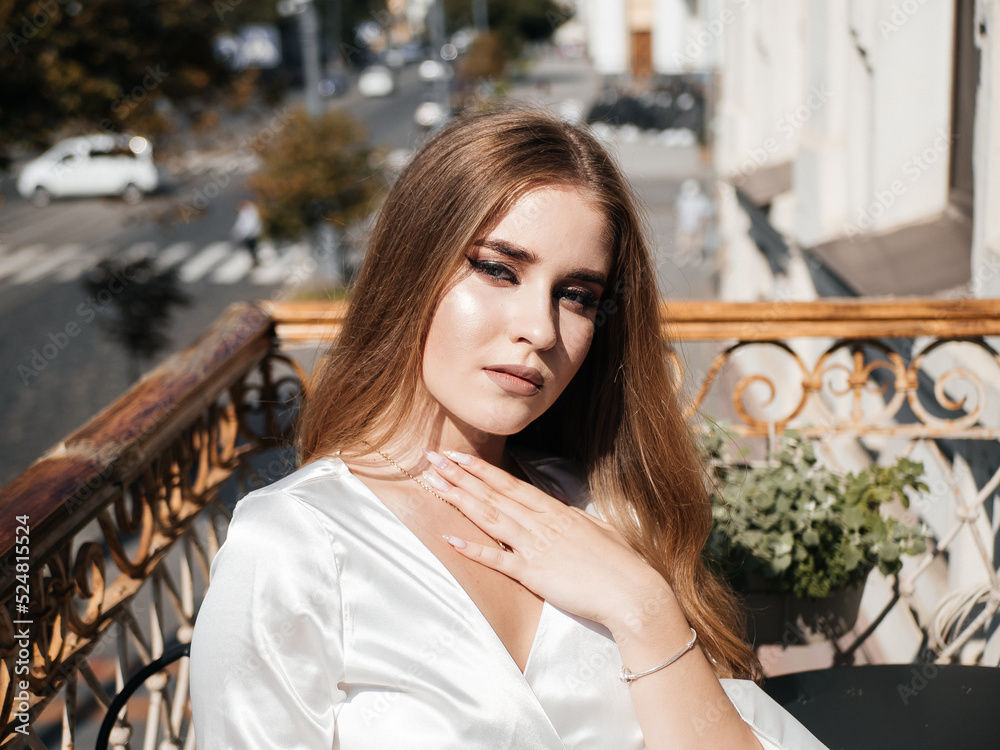 A girl in a white dress poses on the balcony