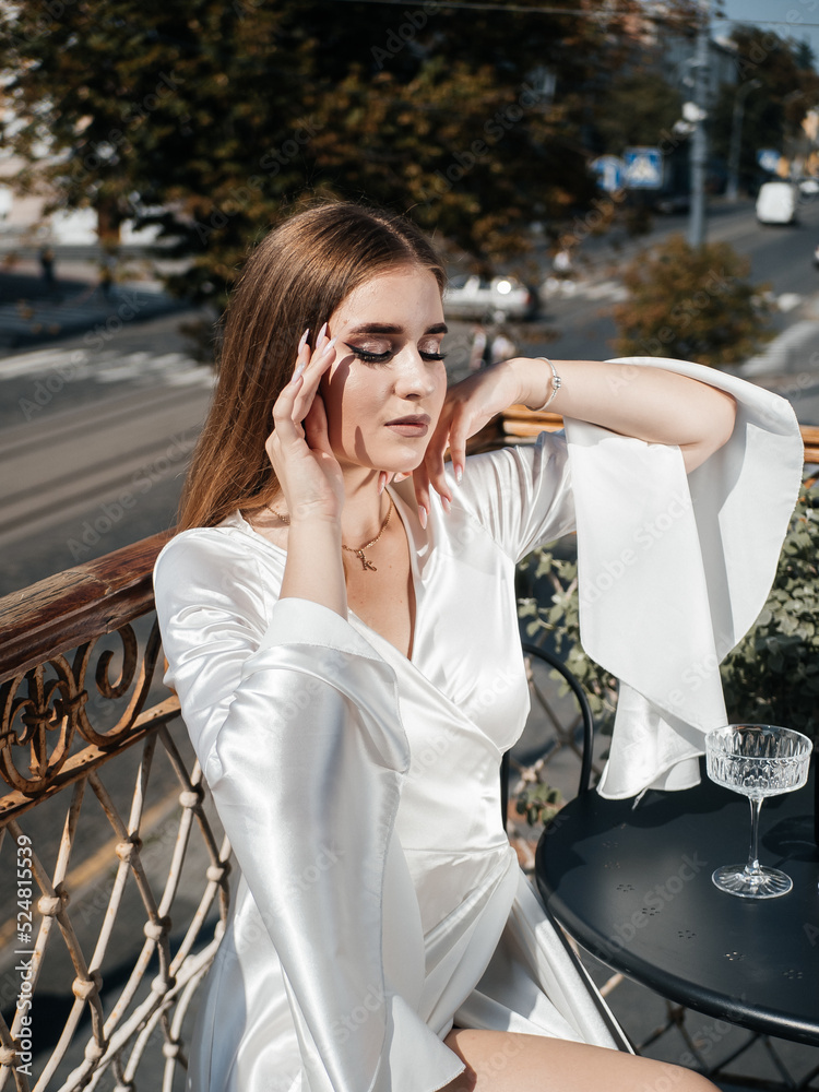 A girl in a white dress poses on the balcony