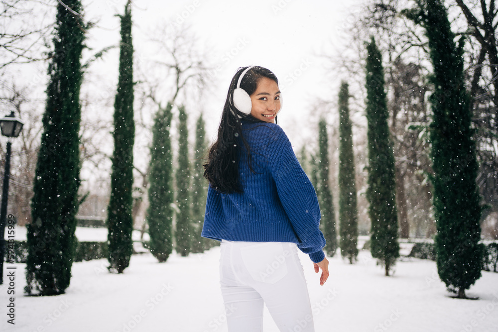 Back view of asian woman under the snow close to park in winter Back view of asian woman under the snow close to park in winter