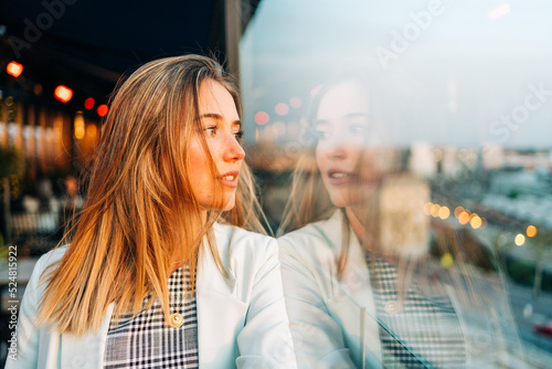 Dreamy woman standing in rooftop restaurant in evening photo