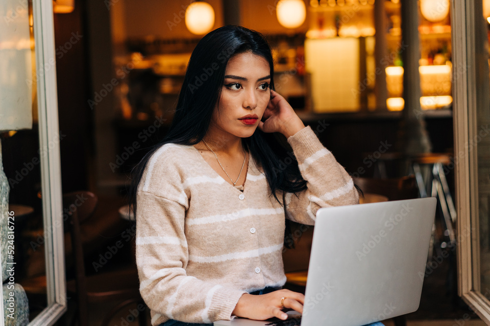Asian woman with laptop on cafe windowsill