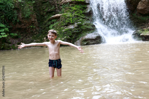 Boy posing in Rufabgo stream next to waterfall Shum