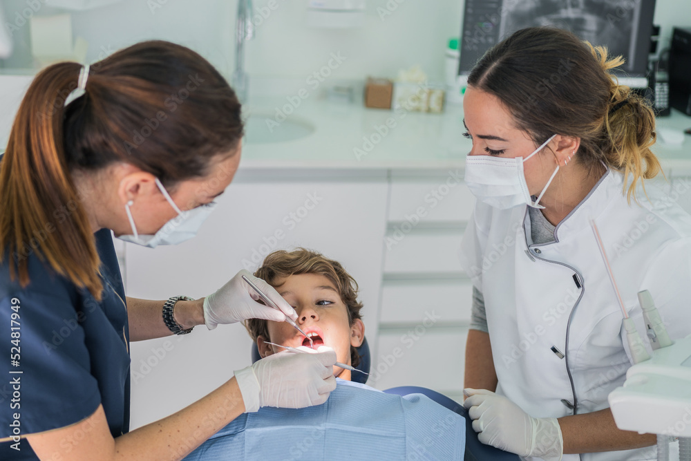Female dentists curing teeth of boy Female dentists curing teeth of boy