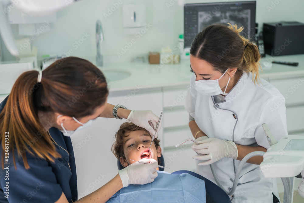 Female dentists curing teeth of boy Female dentists curing teeth of boy