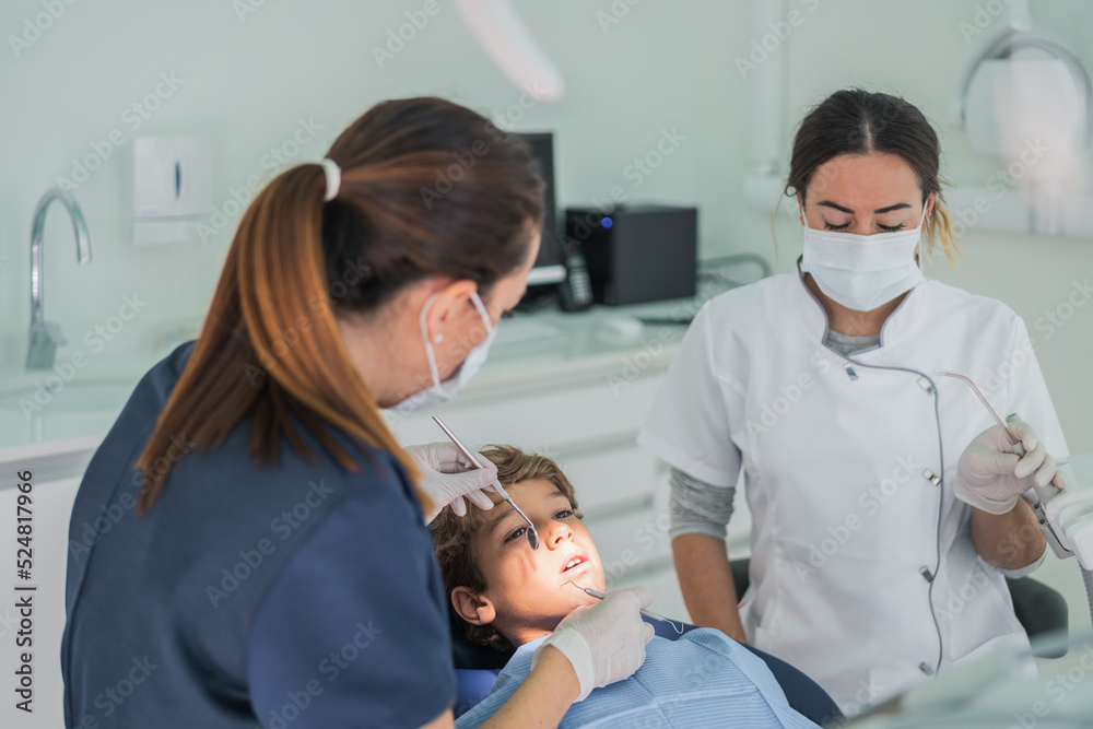 Female dentists curing teeth of boy Female dentists curing teeth of boy