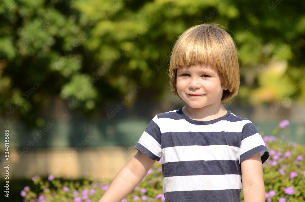 Cute boy, smilling. Close-up portrait against the background of violet flowers. Little boy with beautiful hair Cute boy, smilling. Close-up portrait against the background of violet flowers. Little boy with beautiful hair