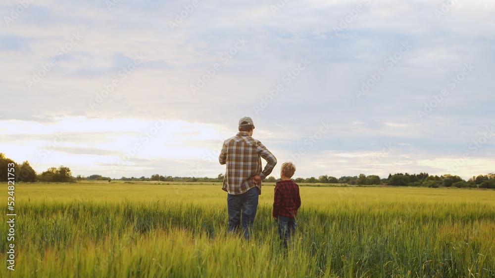 Farmer and his son in front of a sunset agricultural landscape. Man and a boy in a countryside field. Fatherhood, country life, farming and country lifestyle. Farmer and his son in front of a sunset agricultural landscape. Man and a boy in a countryside field. Fatherhood, country life, farming and country lifestyle.