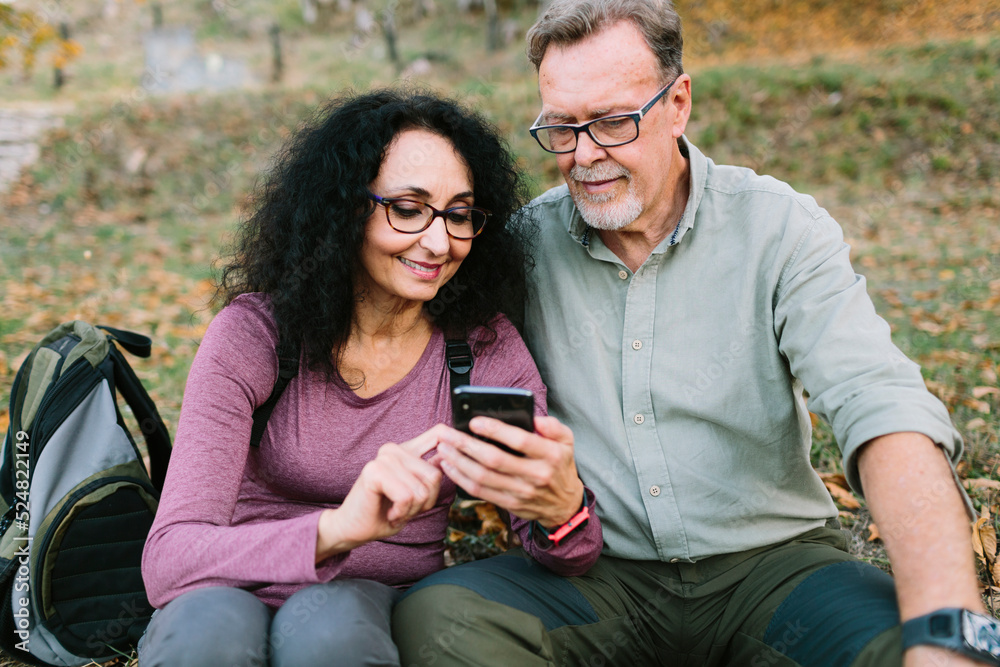 Happy mature couple using smartphone in autumn park Happy mature couple using smartphone in autumn park