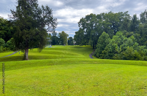 Walking path at prehistoric Great Serpent Mound Earthworks snake effigy in Ohio USA. Body of snake curves along the landscape in largest effigy mound in the world. Dramatic sky woodland background. photo