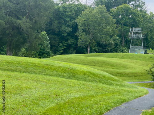 Walking path at prehistoric Great Serpent Mound Earthworks snake effigy in Ohio USA. Body of snake curves along the landscape in the largest effigy mound in the world. Observation tower in background.