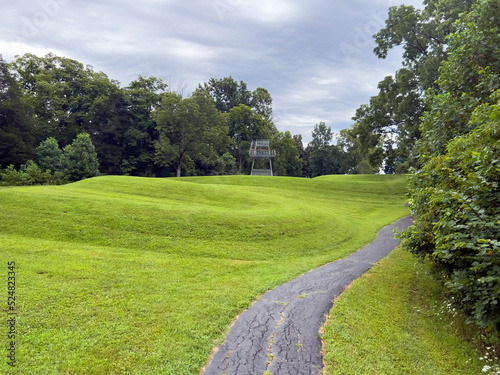 Walking path at prehistoric Great Serpent Mound Earthworks snake effigy in Ohio USA. Body of snake curves along the landscape in the largest effigy mound in the world. Observation tower in background. photo