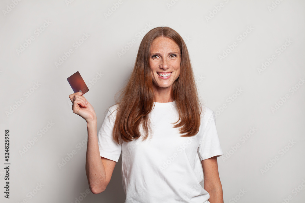Smiling cheerful woman in white t-shirt showing empty credit card on white background Smiling cheerful woman in white t-shirt showing empty credit card on white background