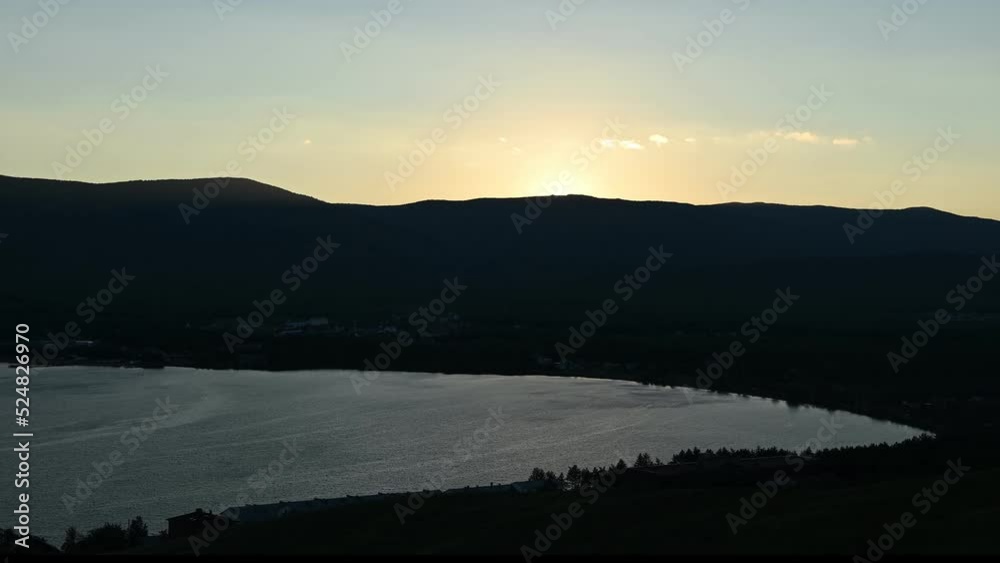 Time lapse of sunset over lake. Sun hiding behind the mountain range Time lapse of sunset over lake. Sun hiding behind the mountain range