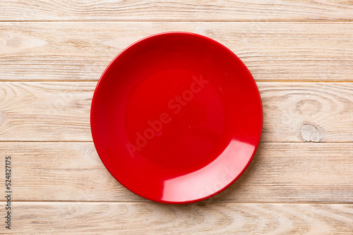 Top view of empty red plate on wooden background. Empty space for your design