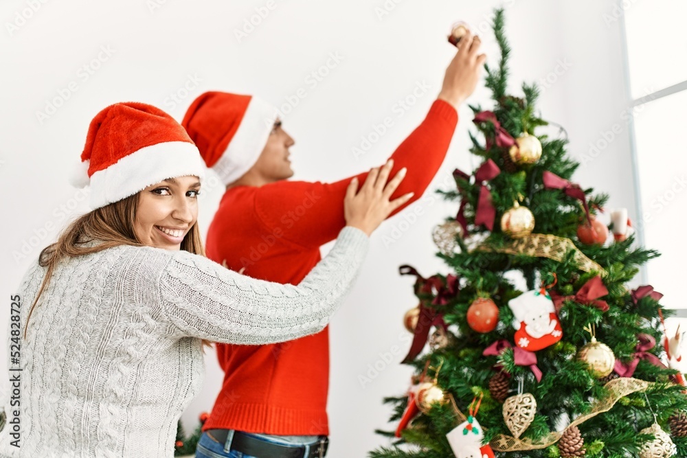 Young couple smiling happy decorating christmas tree at home. Young couple smiling happy decorating christmas tree at home.