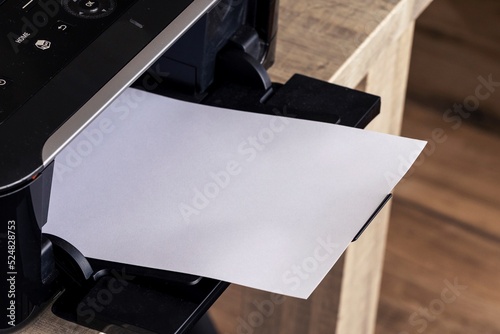 A portrait of a printer with an empty white page in its printed output tray. The blank piece of paper can be used to display some print out.