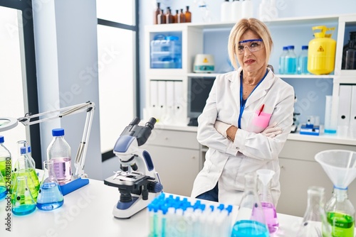 Middle age blonde woman working at scientist laboratory looking sleepy and tired  exhausted for fatigue and hangover  lazy eyes in the morning.