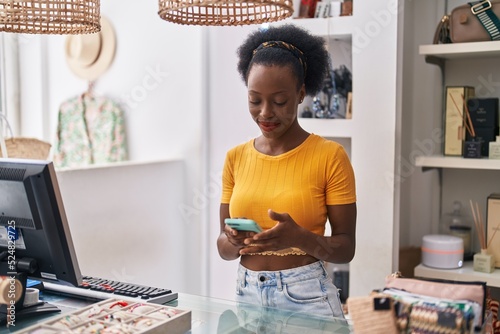 African american woman shop assistant using computer and smartphone at clothing store