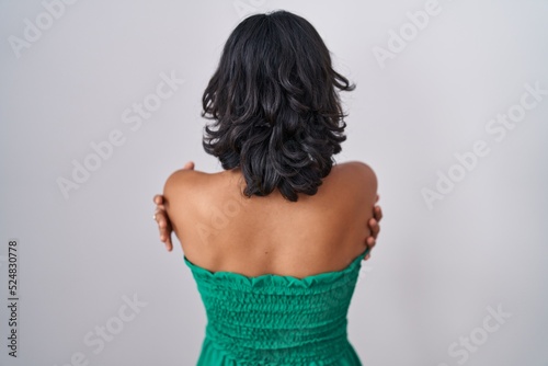 Young hispanic woman standing over isolated background standing backwards looking away with crossed arms