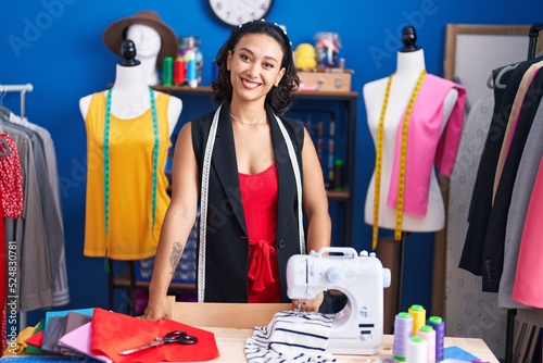 Young beautiful hispanic woman tailor smiling confident standing at clothing factory