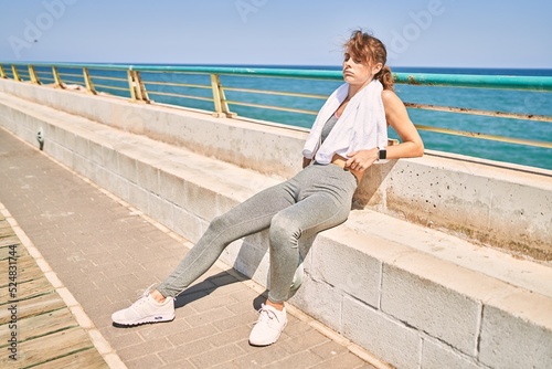 Young caucasian woman wearing sportswear resting at seaside