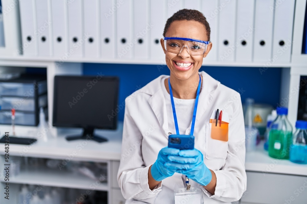 African american woman scientist smiling confident using smartphone at laboratory African american woman scientist smiling confident using smartphone at laboratory