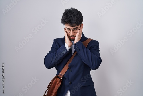 Hispanic man with beard wearing business clothes tired hands covering face, depression and sadness, upset and irritated for problem