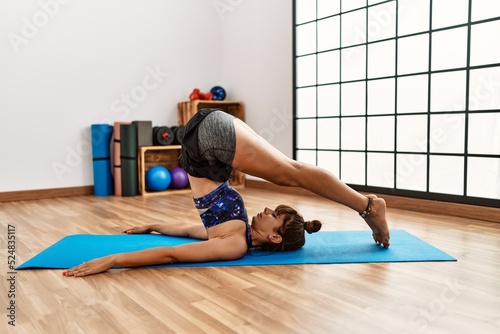 Young hispanic woman stretching at sport center