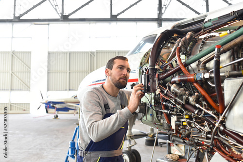 Aircraft mechanic repairs an aircraft engine in an airport hangar photo