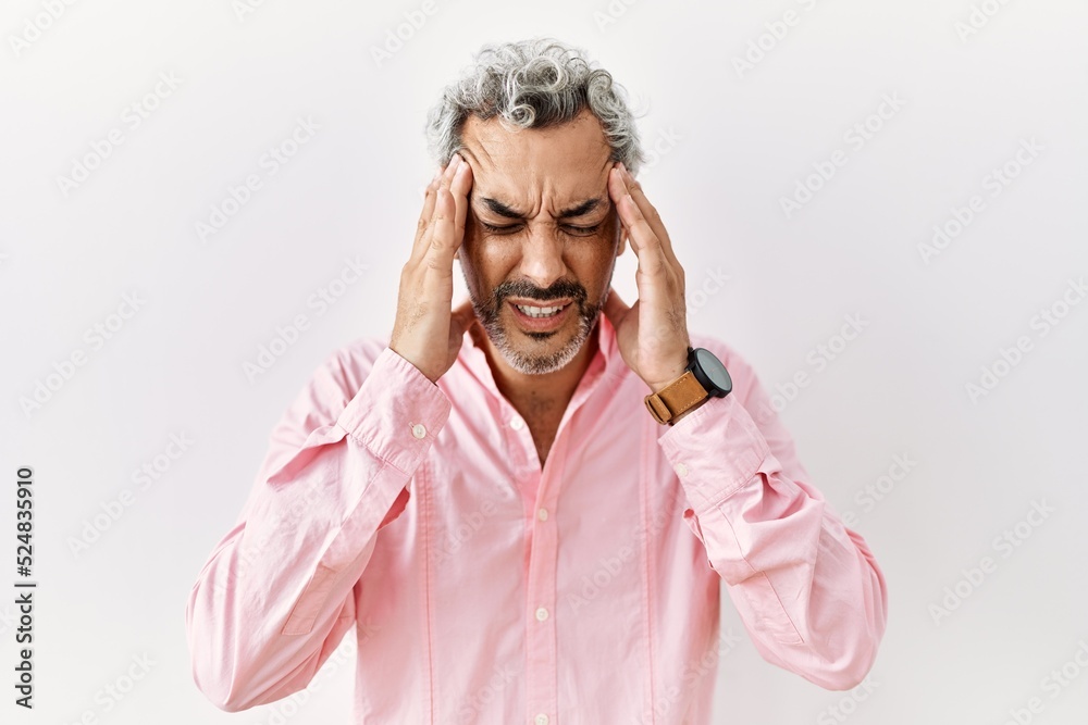 Middle age hispanic man standing over isolated background with hand on head for pain in head because stress. suffering migraine.