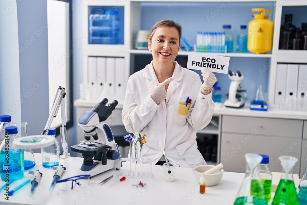Middle age hispanic woman working at eco friendly laboratory smiling happy pointing with hand and finger Middle age hispanic woman working at eco friendly laboratory smiling happy pointing with hand and finger