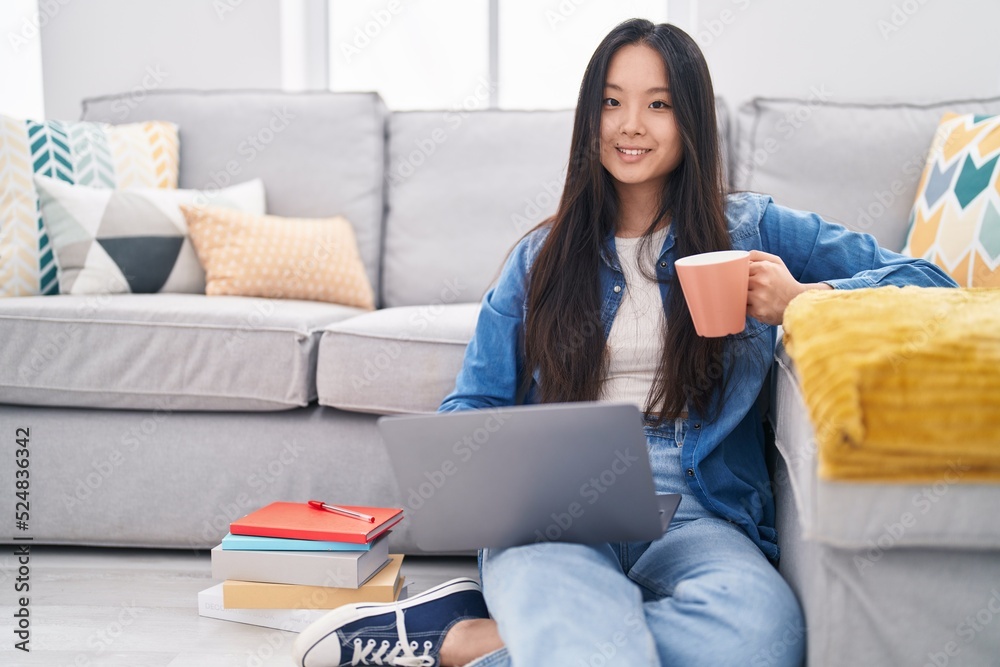 Young chinese woman using laptop drinking coffee at home Young chinese woman using laptop drinking coffee at home