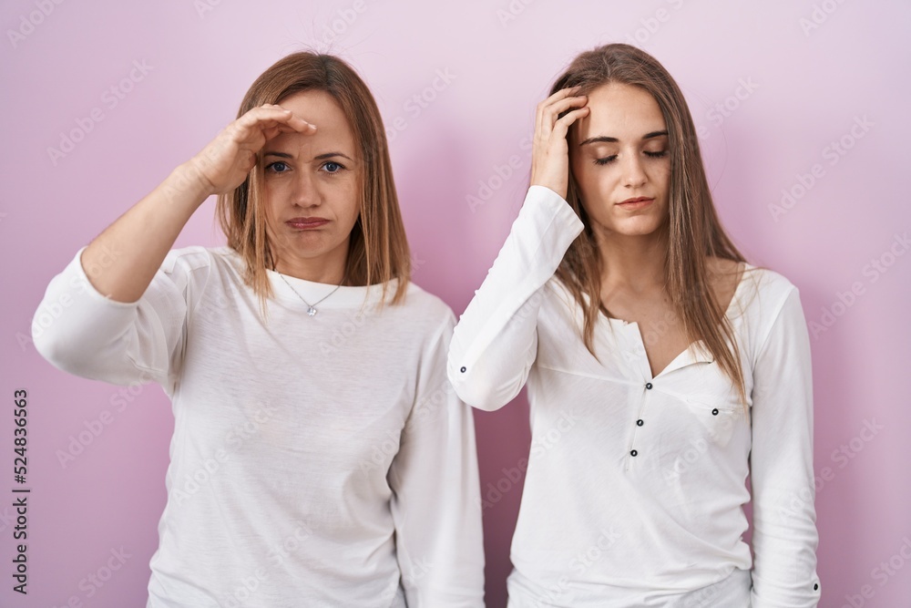 Middle age mother and young daughter standing over pink background worried and stressed about a problem with hand on forehead, nervous and anxious for crisis Middle age mother and young daughter standing over pink background worried and stressed about a problem with hand on forehead, nervous and anxious for crisis