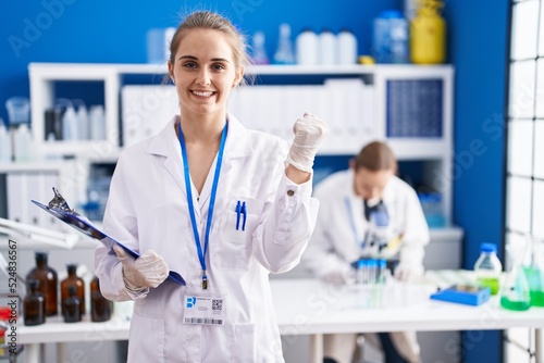 Blonde woman working at scientist laboratory screaming proud  celebrating victory and success very excited with raised arms
