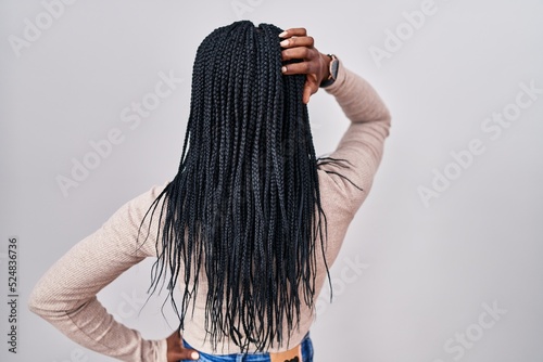 African woman with braids standing over white background backwards thinking about doubt with hand on head