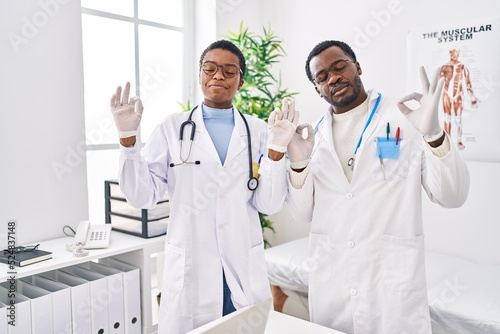 Young african american doctors working at medical clinic relax and smiling with eyes closed doing meditation gesture with fingers. yoga concept.