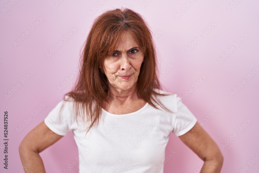 Middle age woman standing over pink background skeptic and nervous, frowning upset because of problem. negative person. Middle age woman standing over pink background skeptic and nervous, frowning upset because of problem. negative person.