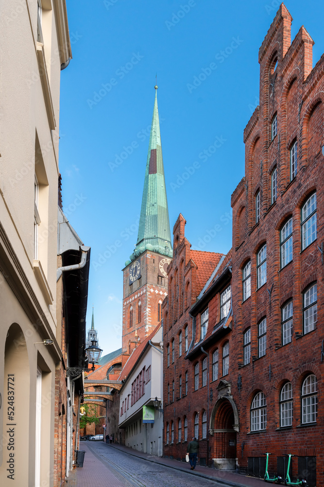 Fototapeta premium Street in Lübeck with tradional buildings und view to the tower of the church St. Jakobi