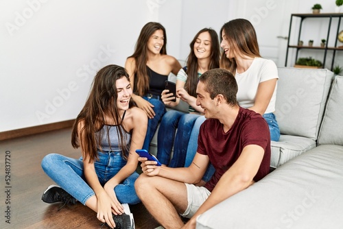Group of young hispanic friends smiling happy using smartphone sitting on the sofa at home.