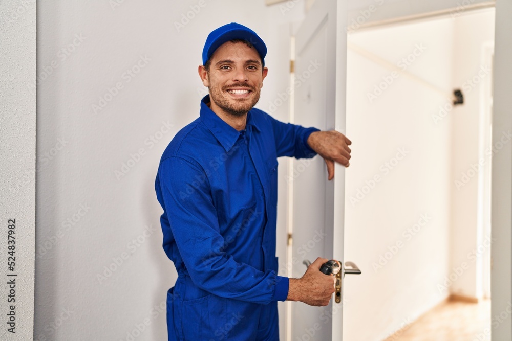 Young hispanic man technician repairing door at home