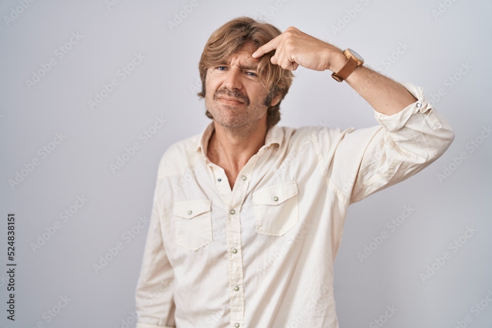 Middle age man standing over isolated background pointing unhappy to pimple on forehead, ugly infection of blackhead. acne and skin problem Middle age man standing over isolated background pointing unhappy to pimple on forehead, ugly infection of blackhead. acne and skin problem