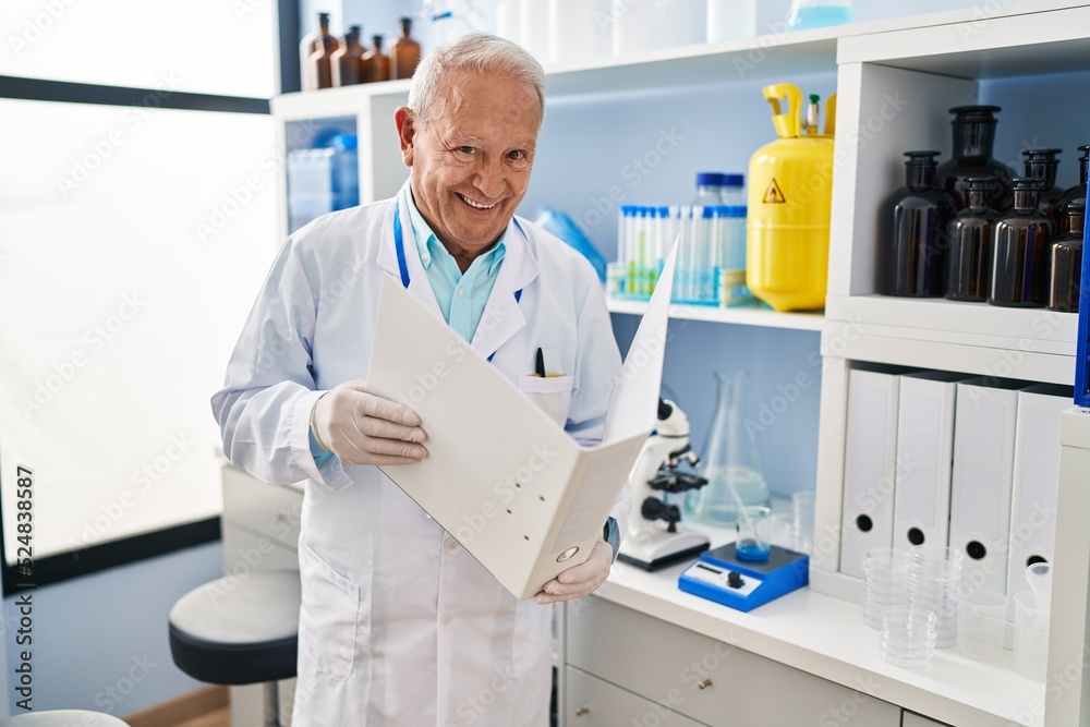 Senior man wearing scientist uniform reading document at laboratory Senior man wearing scientist uniform reading document at laboratory