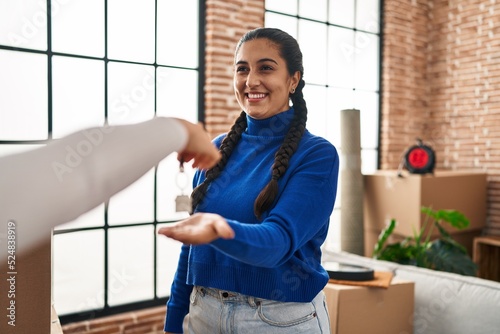 Young hispanic woman smiling confident reciving key of new house at new home