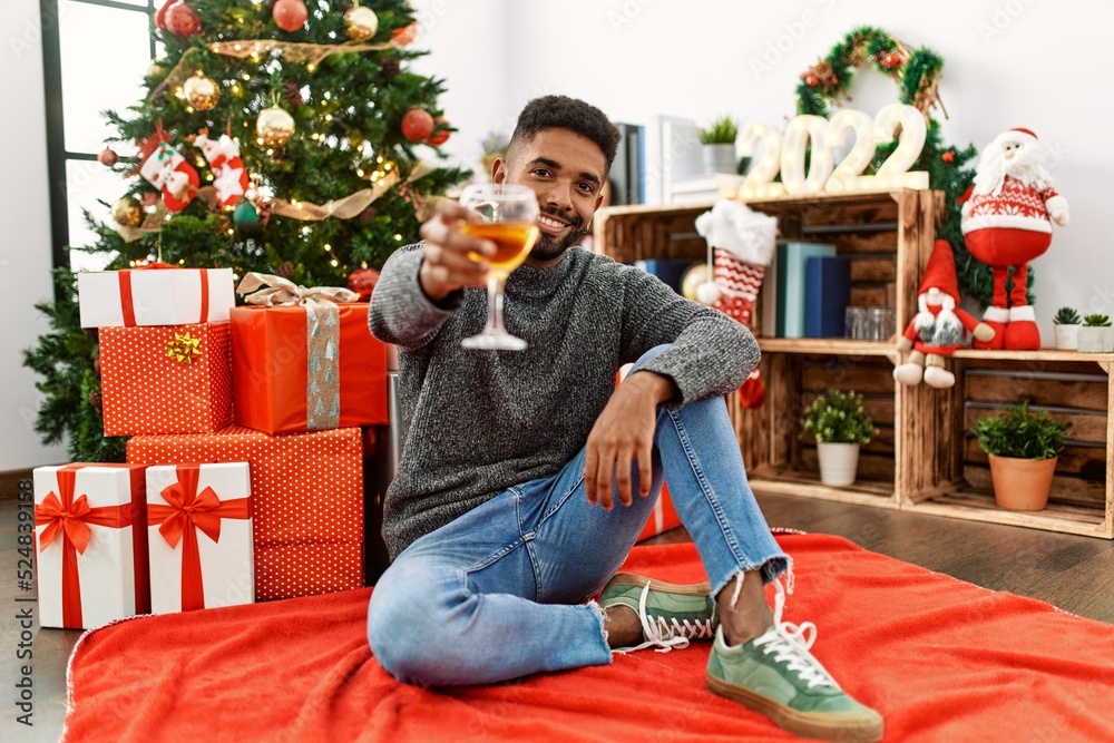 Young african american man smiling happy celebrating christmas drinking champagne at home. Young african american man smiling happy celebrating christmas drinking champagne at home.