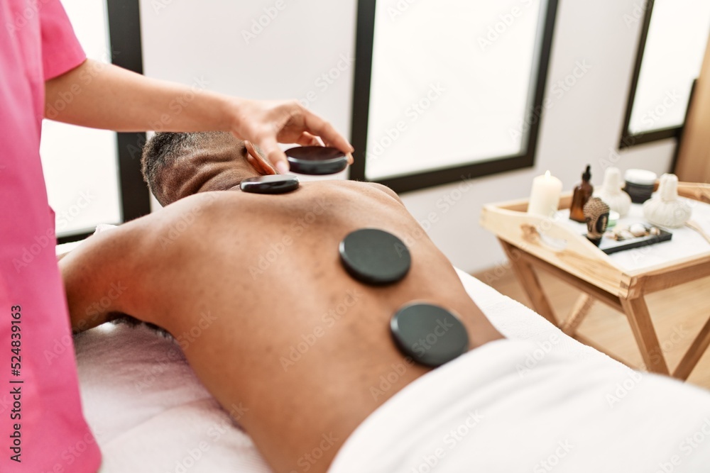 Man reciving back massage with black stones at beauty center. Man reciving back massage with black stones at beauty center.