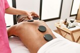 Man reciving back massage with black stones at beauty center.