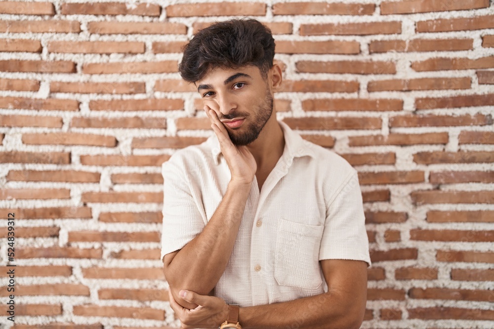 Arab man with beard standing over bricks wall background thinking looking tired and bored with depression problems with crossed arms. Arab man with beard standing over bricks wall background thinking looking tired and bored with depression problems with crossed arms.