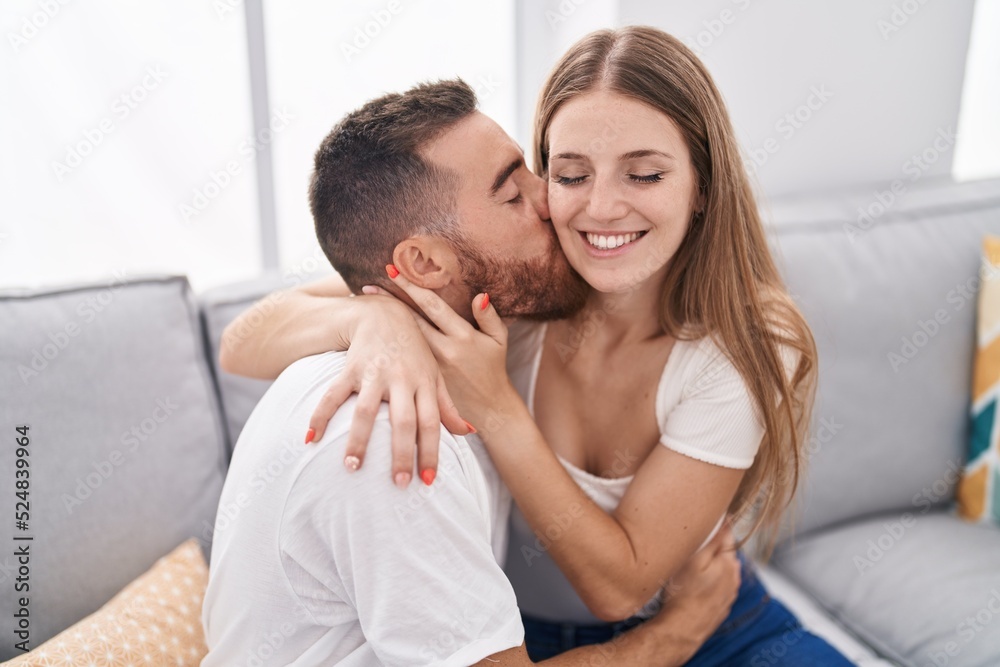 Man and woman couple sitting on sofa kissing at home Man and woman couple sitting on sofa kissing at home