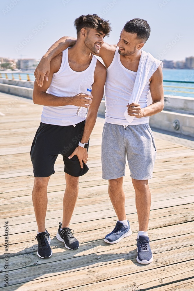 Two hispanic men sporty couple smiling confident and hugging each other standing at seaside Two hispanic men sporty couple smiling confident and hugging each other standing at seaside